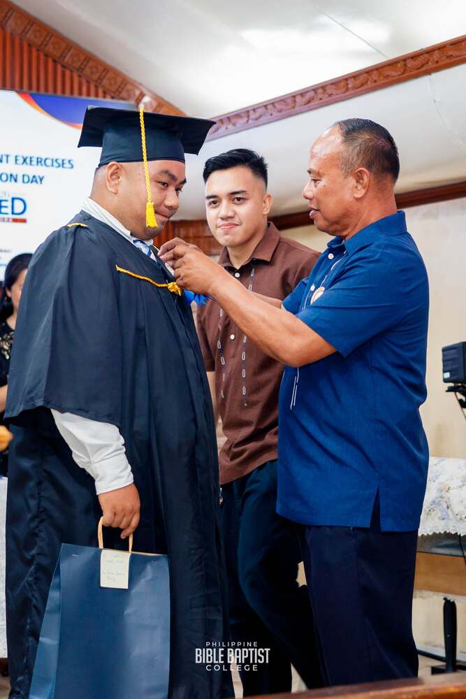 A graduate being pinned by Dr. Edgar Nono during the commencement exercises